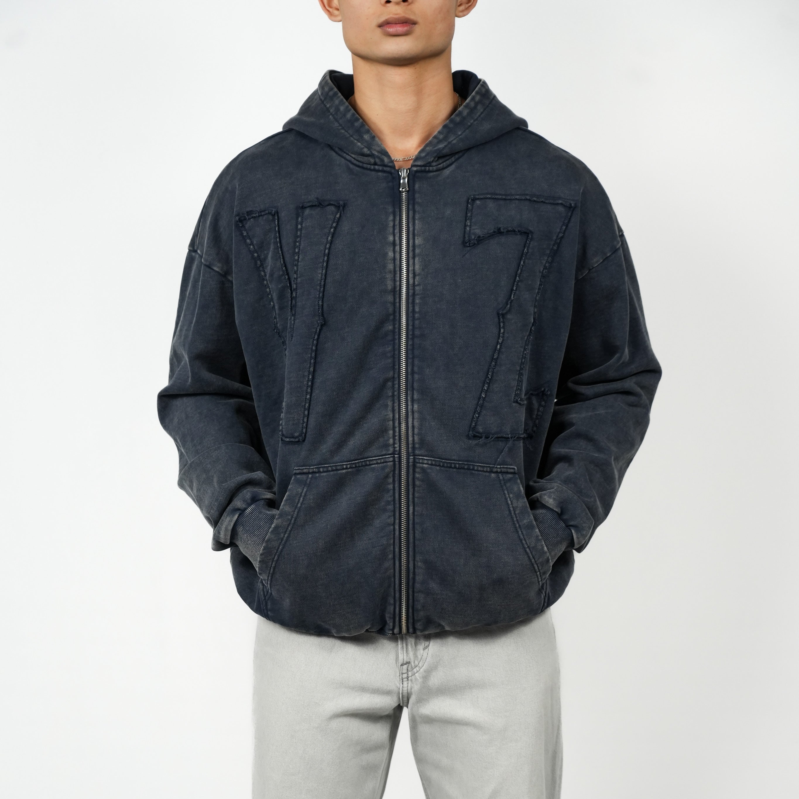 Person wearing a dark blue jacket and light gray pants on a white background