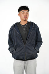 Man wearing a dark blue hoodie over a black shirt with visible branding on a white background