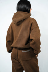 Person wearing a brown tracksuit with 'Discipline in Motion' branding on a white background