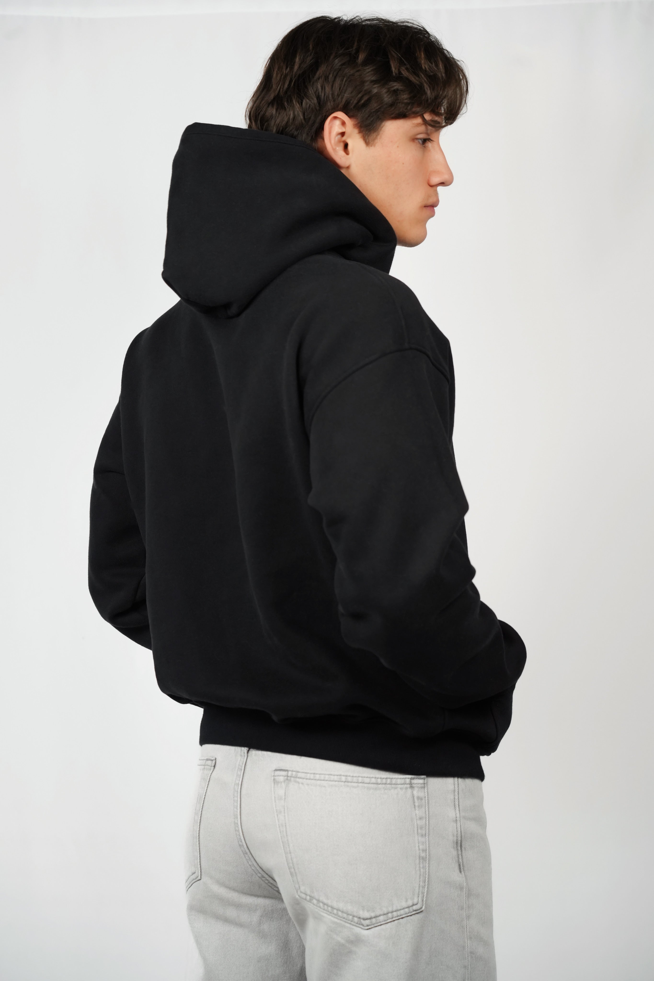 Person wearing a black hoodie from behind on a white background
