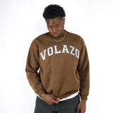 Person wearing a brown sweatshirt with 'VOLAZO' text on a white background