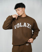 Person wearing a brown 'VOLAZO' sweatshirt and pants on a plain background