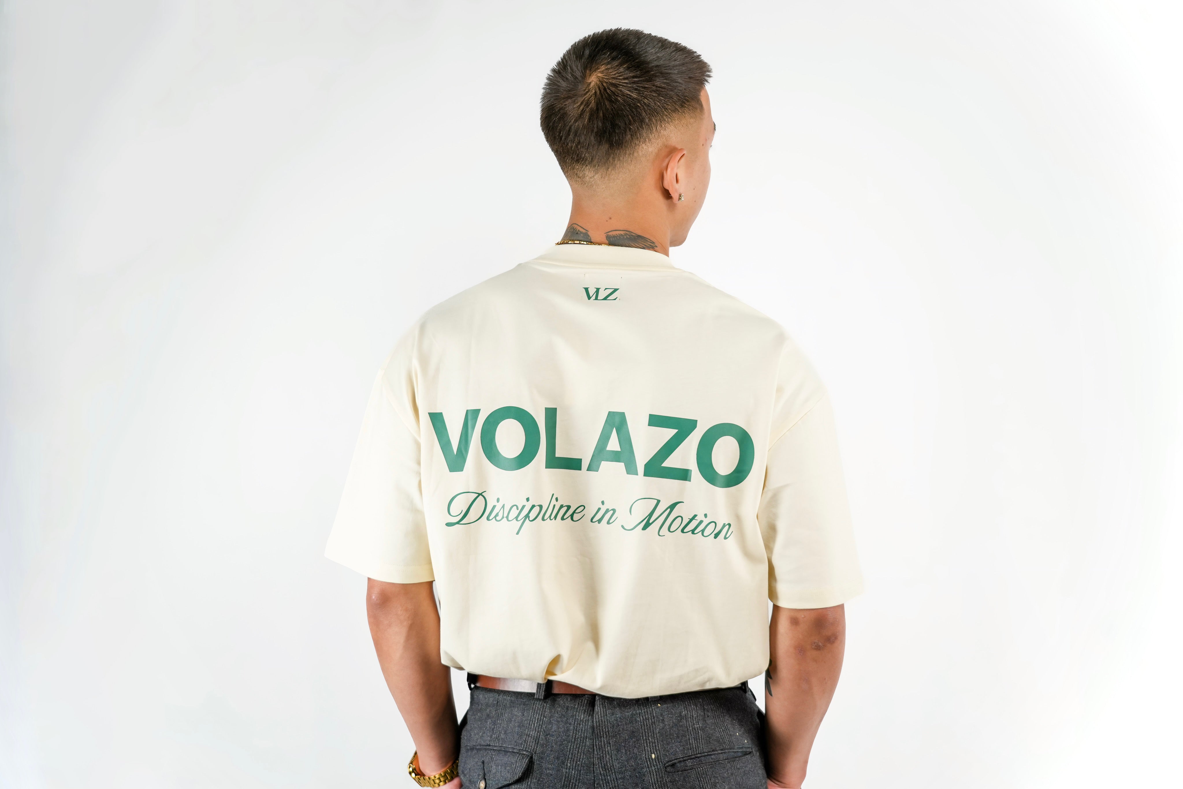 Person wearing a bone creme with 'VOLAZO' branding on the back against a white background