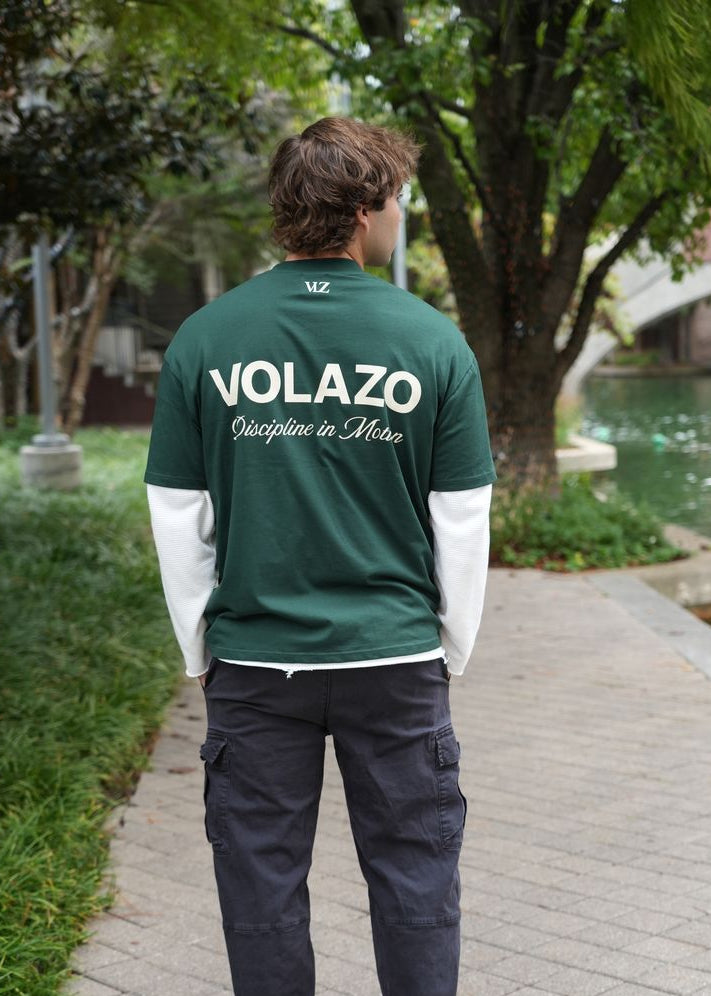 Person wearing a green 'VOLAZO' shirt walking outdoors on a path.