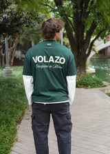 Person wearing a green 'VOLAZO' shirt walking outdoors on a path.